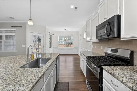 a kitchen with stainless steel appliances granite countertop a stove a sink dishwasher and microwave with wooden floor