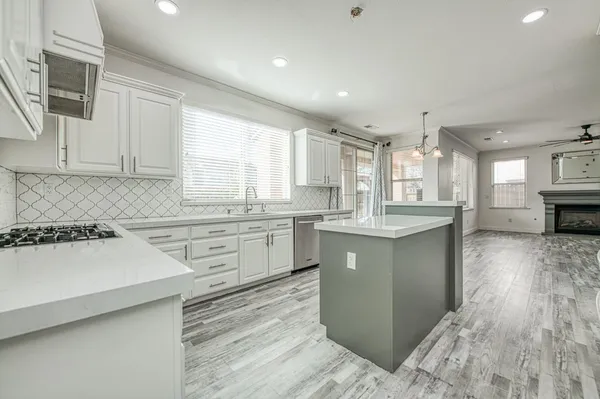 a kitchen with a sink dishwasher a stove a refrigerator and cabinets with wooden floor