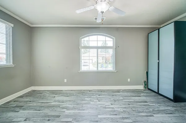 a view of empty room with wooden floor and fan