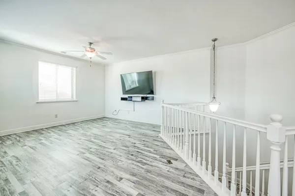 a view of empty room with wooden floor and fan