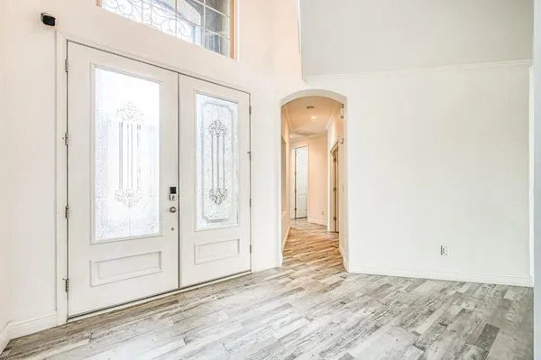a view of an empty room with wooden floor fireplace and a window