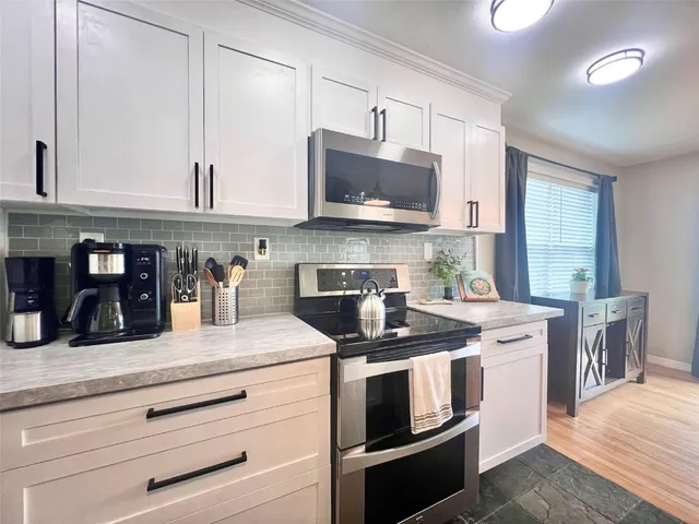 a kitchen with stainless steel appliances granite countertop a stove a sink and a microwave