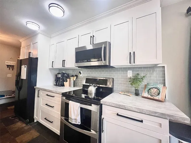 a kitchen with white cabinets and appliances