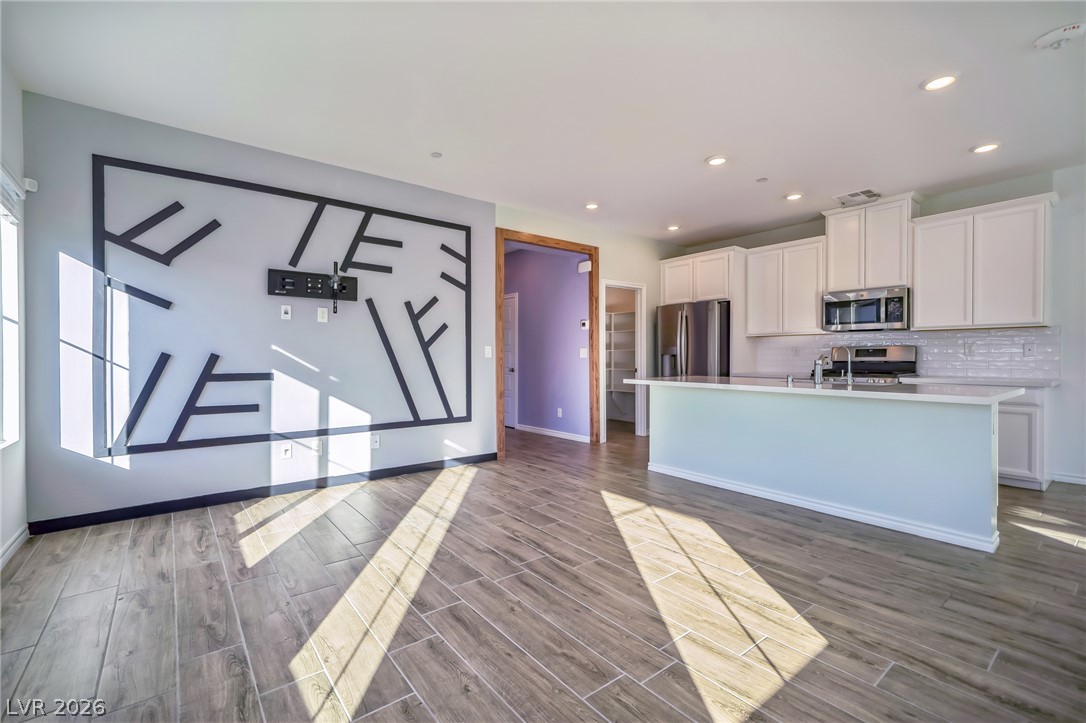 7348 North Decatur Boulevard, Unit 1 North Las Vegas, NV 89084 - Photo 2 of 17 An open-concept interior features wood-look tile flooring and recessed lighting throughout, connecting a living area to a modern kitchen.