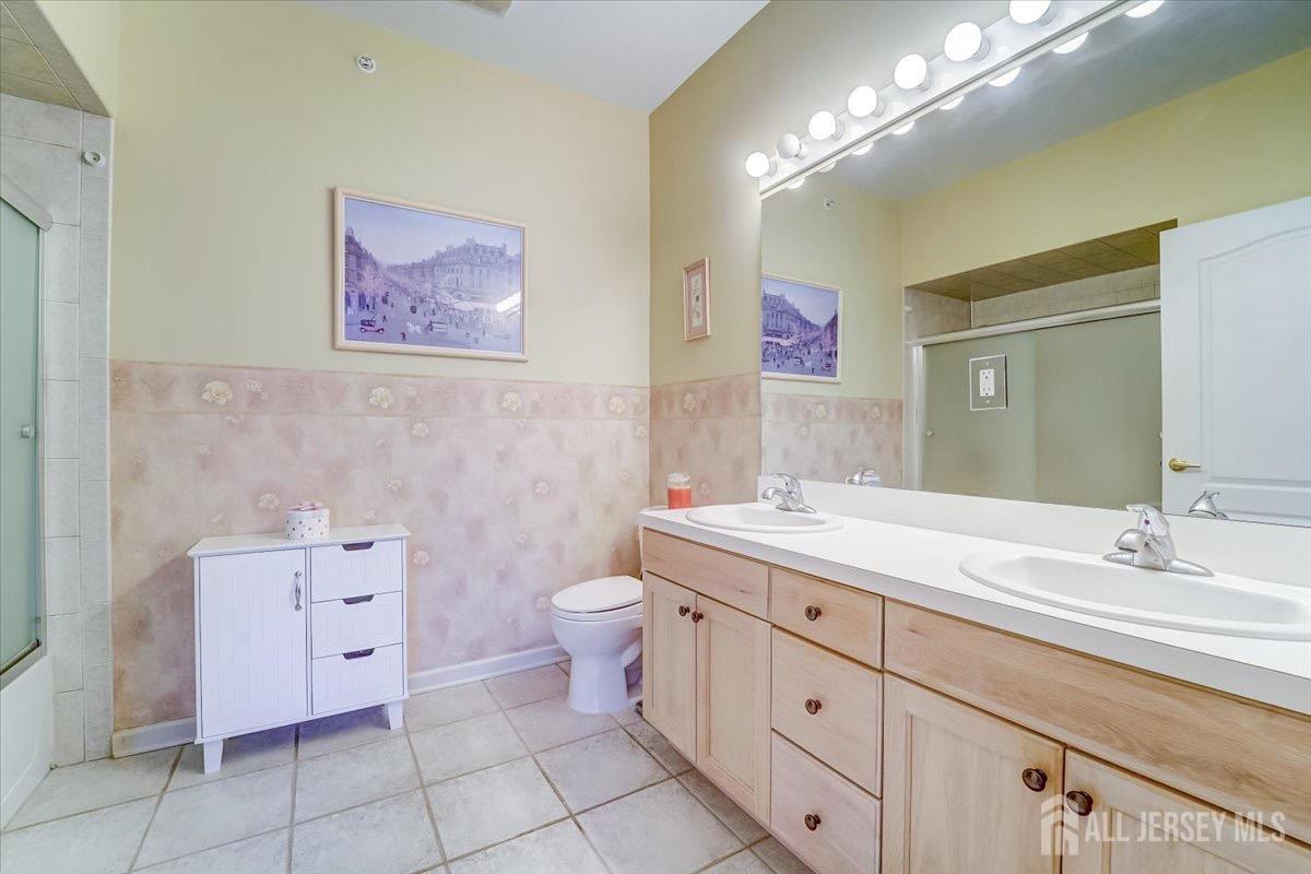 375 Rifle Camp Road, Unit 409 Woodland Park, NJ 07424 - Photo 18 of 22 a bathroom with a double vanity sink a toilet and a mirror