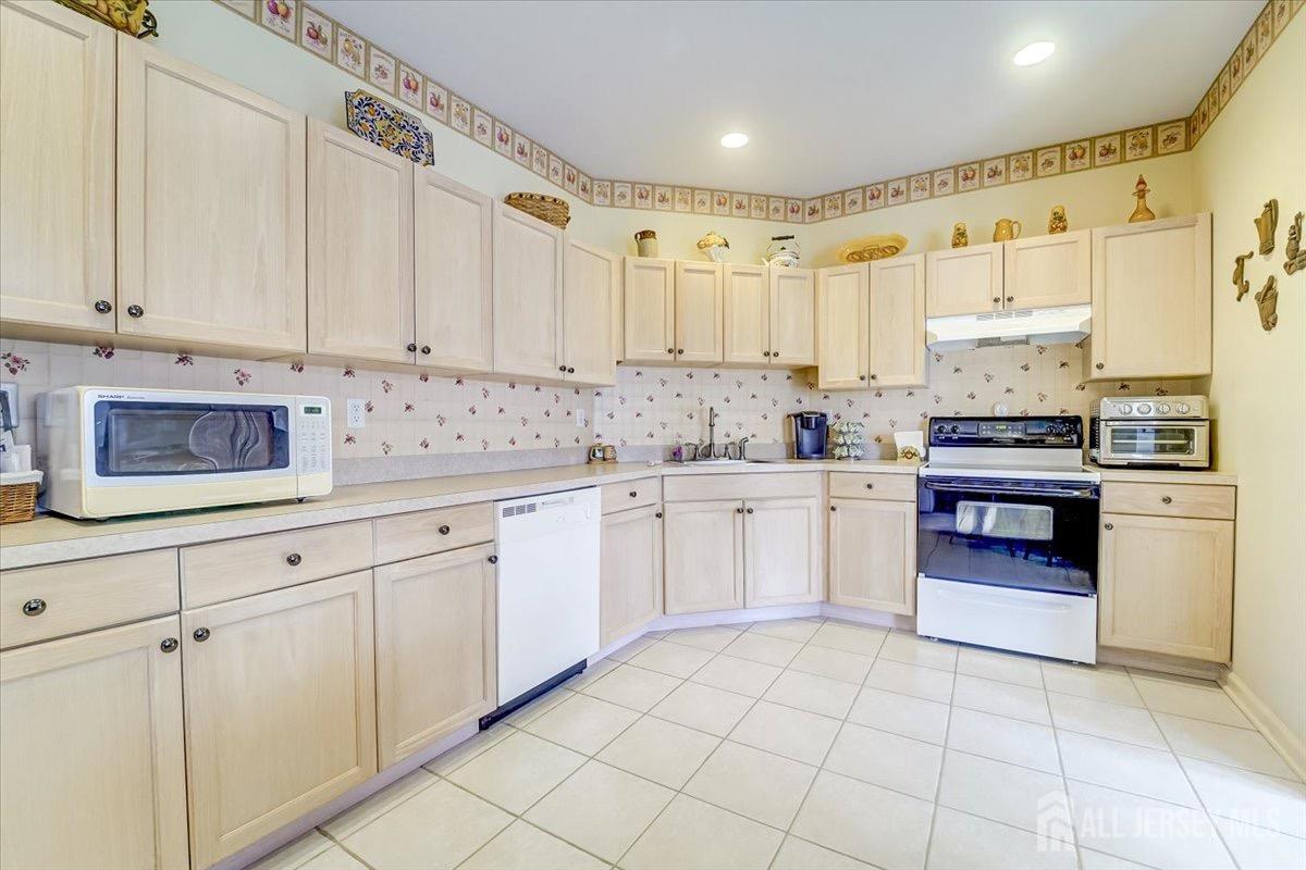375 Rifle Camp Road, Unit 409 Woodland Park, NJ 07424 - Photo 10 of 22 a kitchen with kitchen island granite countertop white cabinets white stainless steel appliances with a sink and dishwasher