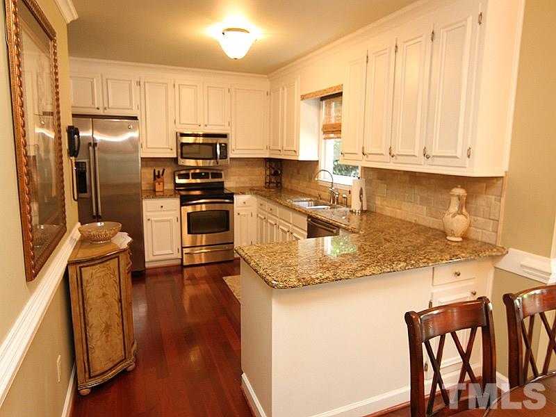 2712 Farnborough Road Raleigh, NC 27613 - Photo 5 of 25 Remodeled Kitchen features white painted cabinets, SS appliances and granite counter tops. 2 pantry/storage closets and breakfast room with bay window overlooking private backyard.