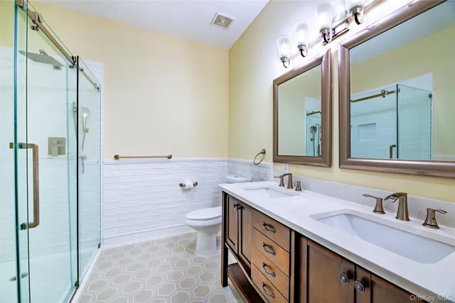 a bathroom with a double vanity sink mirror and toilet