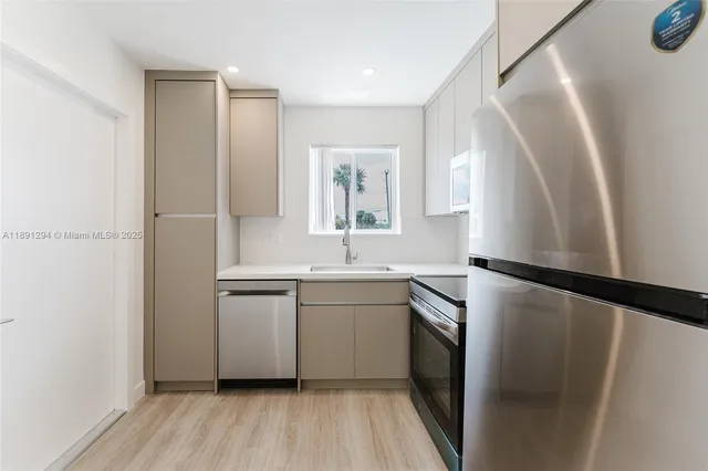 a kitchen with a sink a refrigerator a washer and dryer with wooden floor