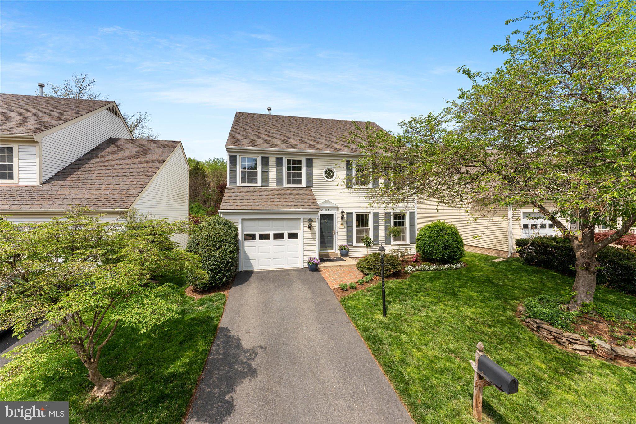 a front view of a house with a garden and trees