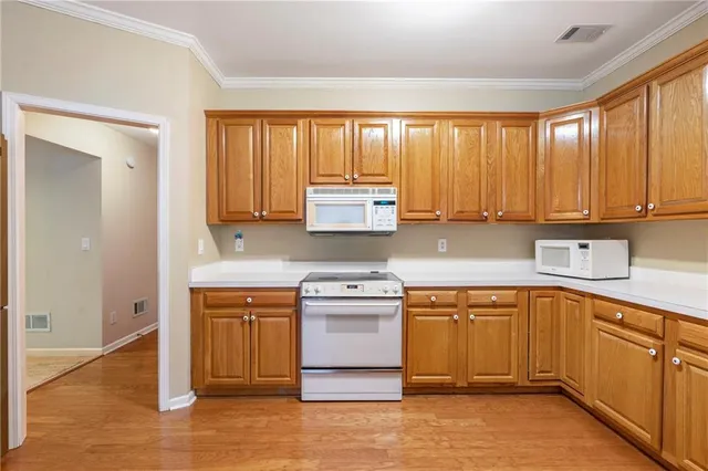 a kitchen with stainless steel appliances a refrigerator a sink dishwasher a oven with white cabinets and wooden floor