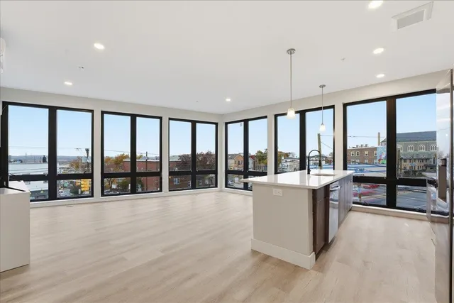 a living room with stainless steel appliances furniture a flat screen tv and a view of kitchen