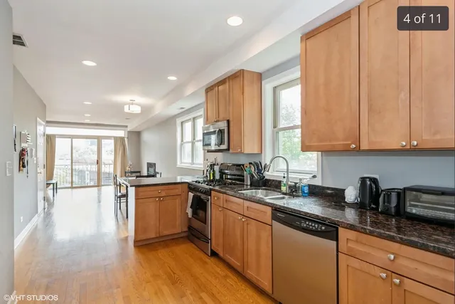 a kitchen with stainless steel appliances granite countertop wooden cabinets a sink dishwasher a stove and a refrigerator with wooden floor