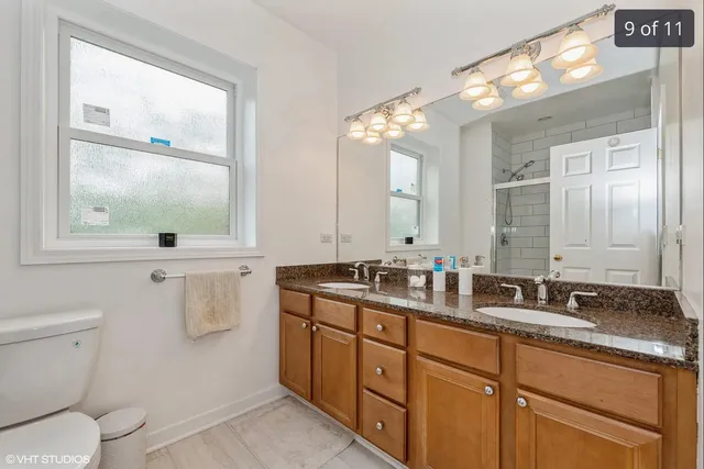 a bathroom with a double vanity sink toilet and a mirror