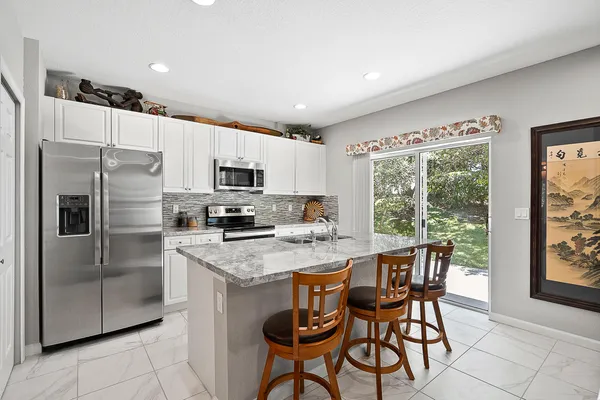 a kitchen with stainless steel appliances granite countertop a stove a refrigerator a sink dishwasher a dining table and chairs with wooden floor