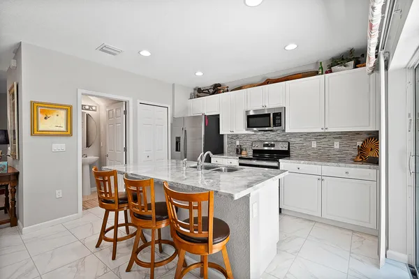 a kitchen with stainless steel appliances granite countertop a stove top oven a sink dishwasher a dining table and chairs with wooden floor