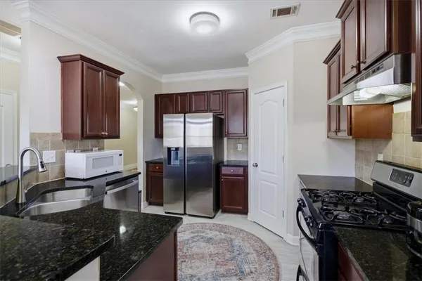 a kitchen with granite countertop a sink stove and refrigerator