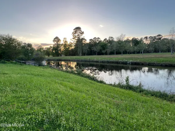 a view of a lake with a yard and large trees