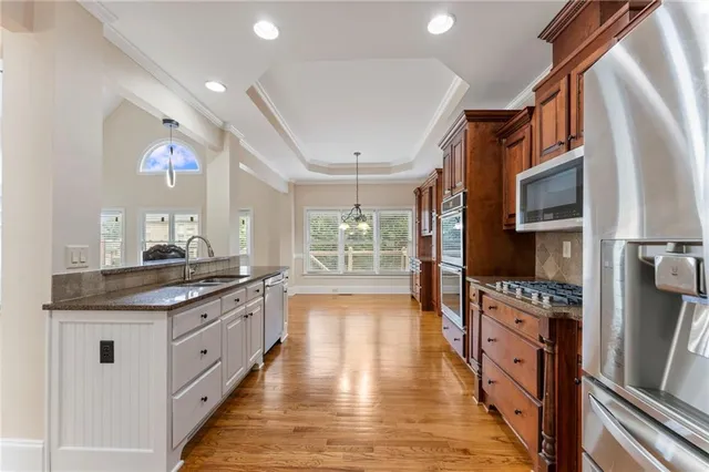 an empty room with wooden floor chandelier fan and windows