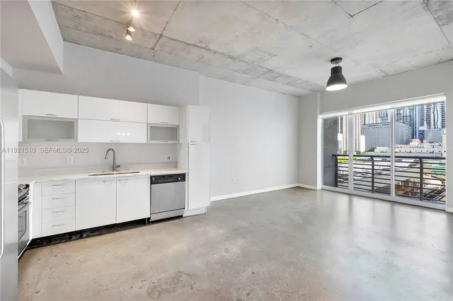 a kitchen with granite countertop a stove a sink and white cabinets with wooden floor