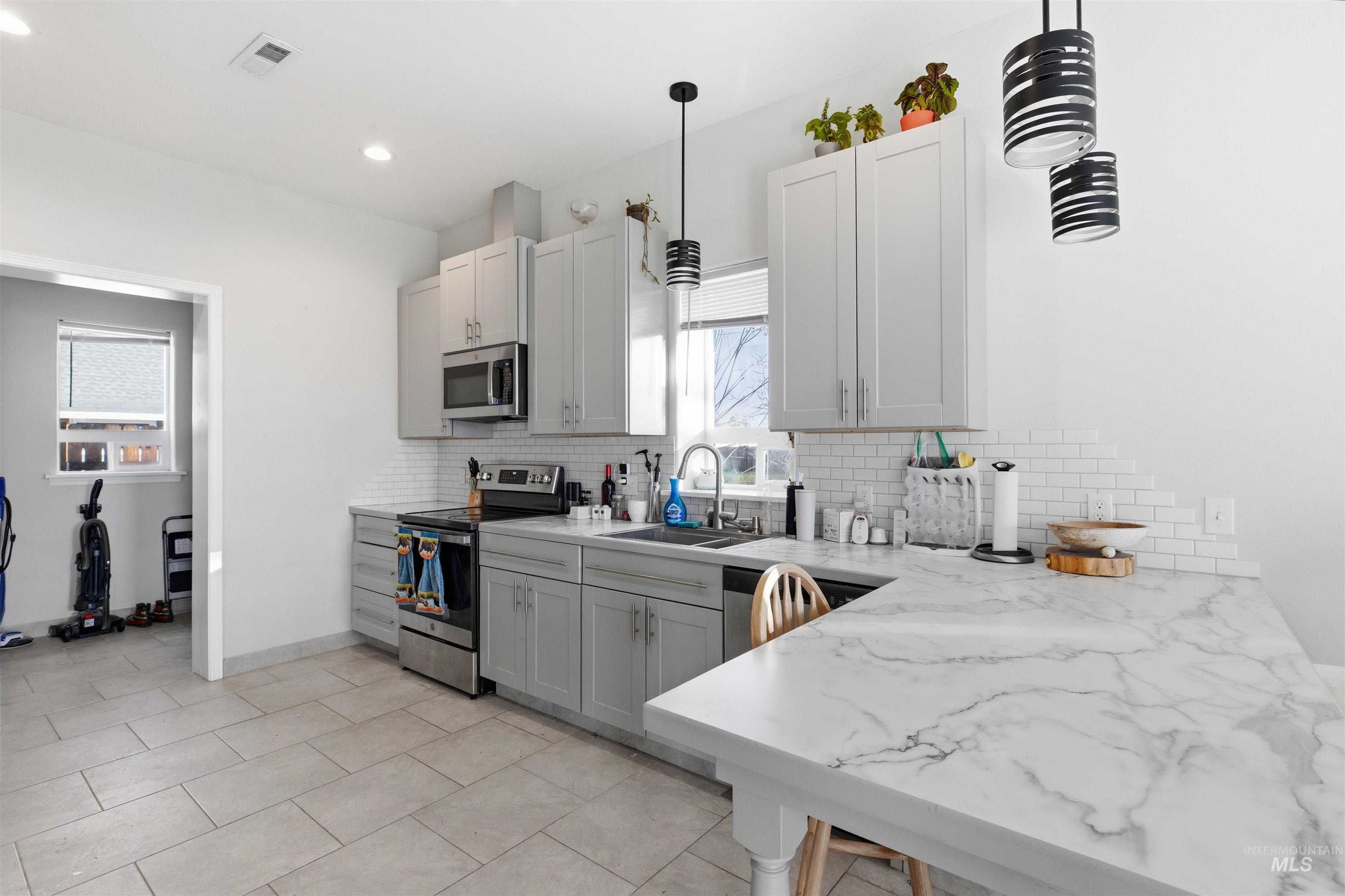 350 East Walnut Avenue Genesee, ID 83832 - Photo 5 of 27 Kitchen with stainless steel appliances, light stone countertops, decorative backsplash, light tile patterned flooring, and decorative light fixtures