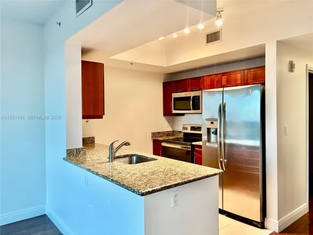 a kitchen with stainless steel appliances granite countertop a sink and a refrigerator
