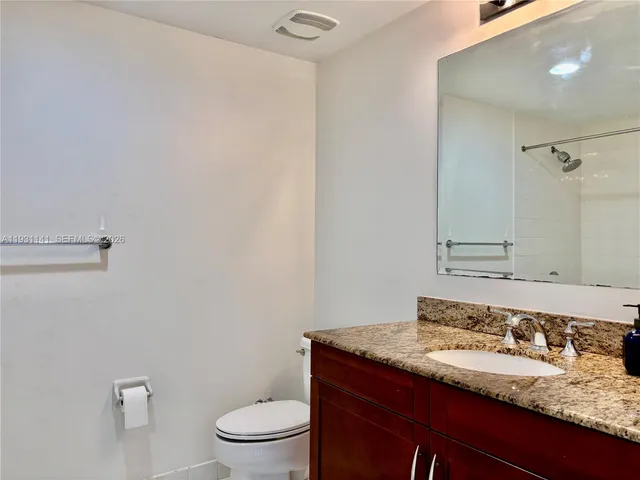 a bathroom with a granite countertop sink a toilet and a mirror
