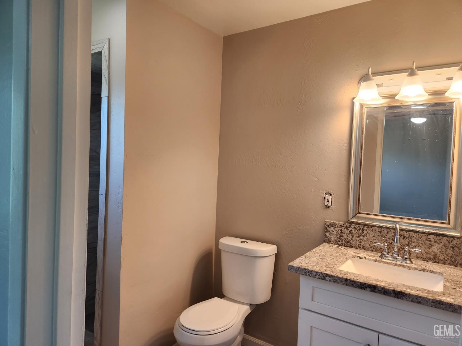 Undisclosed Address Bakersfield, CA 93309 - Photo 19 of 22 a bathroom with a granite countertop sink mirror and toilet