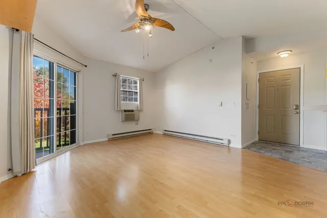 an empty room with chandelier fan and windows