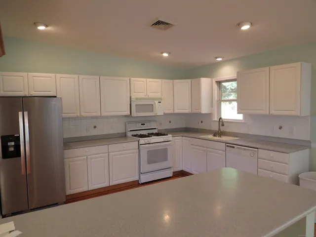 a kitchen with granite countertop white cabinets and white appliances