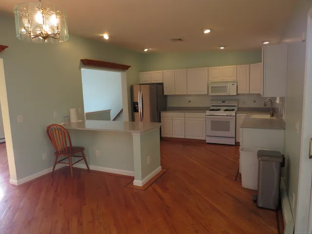 a kitchen with kitchen island granite countertop wooden floors and stainless steel appliances