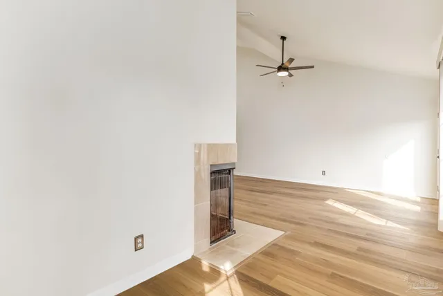 a view of empty room with wooden floor and ceiling fan
