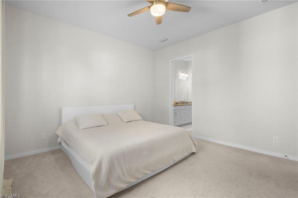 14720 Kingfisher Loop Naples, FL 34120 - Photo 26 of 50 Bedroom with ceiling fan, light carpet, and ensuite bath