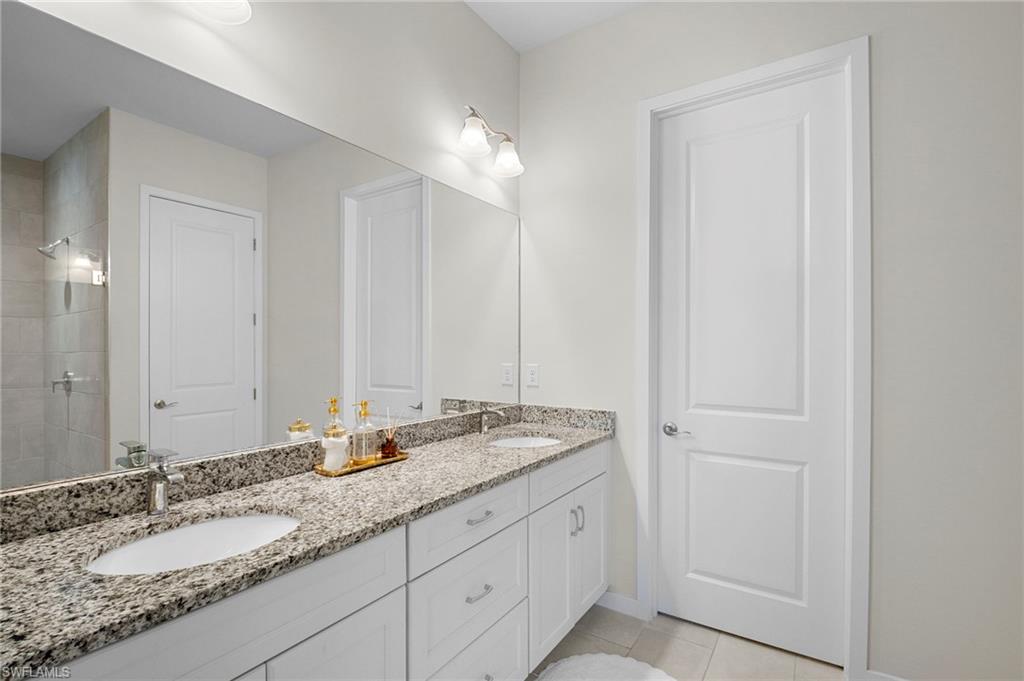 14720 Kingfisher Loop Naples, FL 34120 - Photo 29 of 50 Full bathroom with double vanity, a tile shower, and light tile patterned flooring