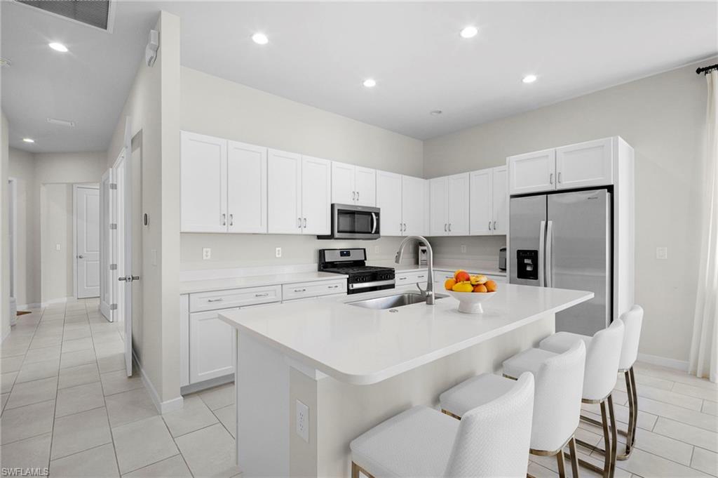 14720 Kingfisher Loop Naples, FL 34120 - Photo 4 of 50 Kitchen featuring white cabinetry, stainless steel appliances, a breakfast bar area, a kitchen island with sink, and recessed lighting