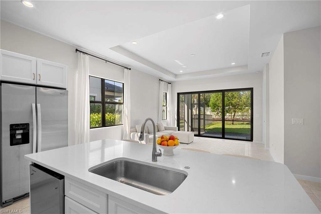 14720 Kingfisher Loop Naples, FL 34120 - Photo 8 of 50 Kitchen with stainless steel fridge, healthy amount of natural light, light tile patterned flooring, recessed lighting, and a raised ceiling