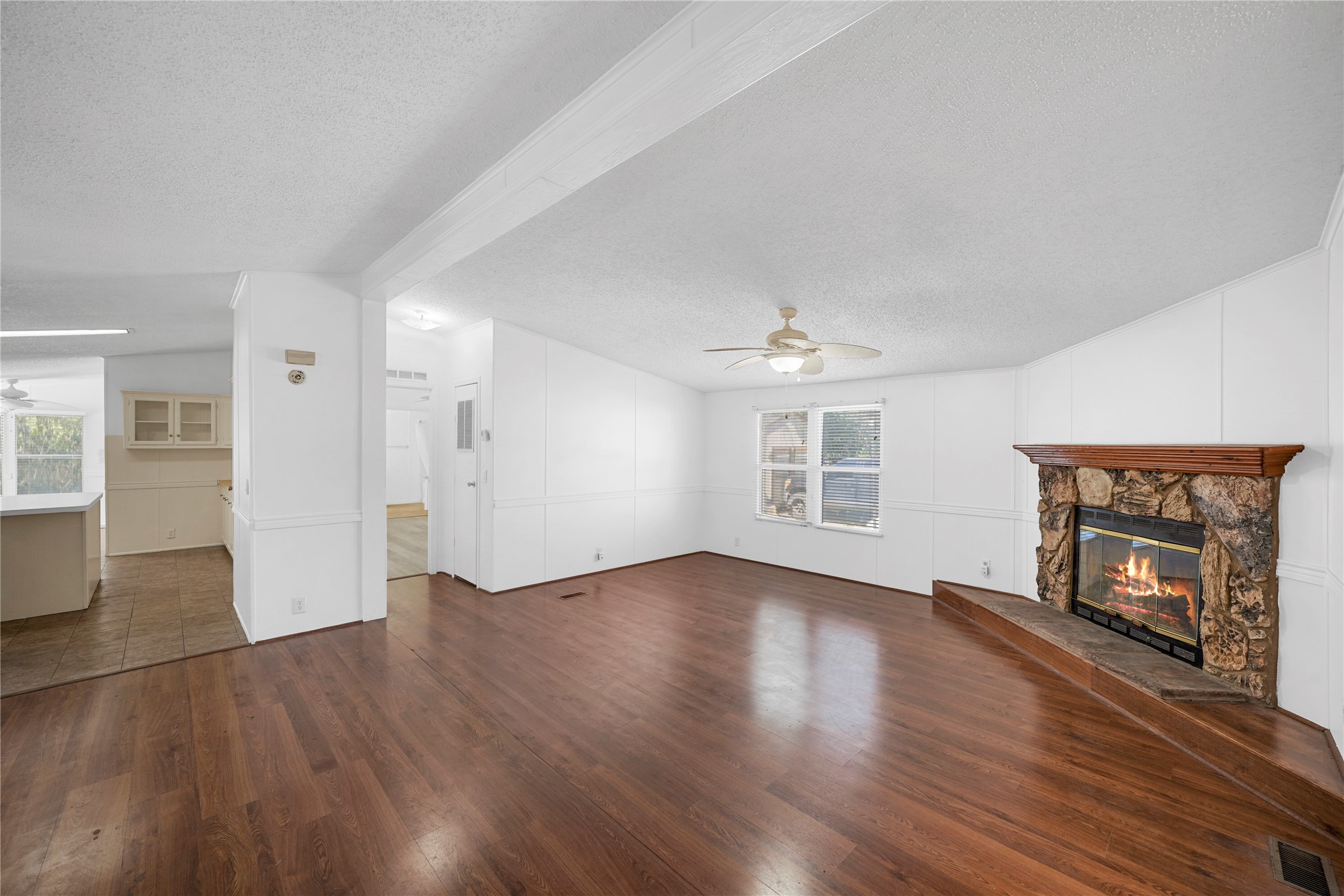 an empty room with wooden floor fireplace and windows