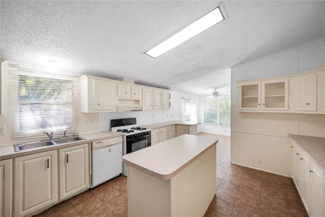 a kitchen that has a sink a stove and white cabinets