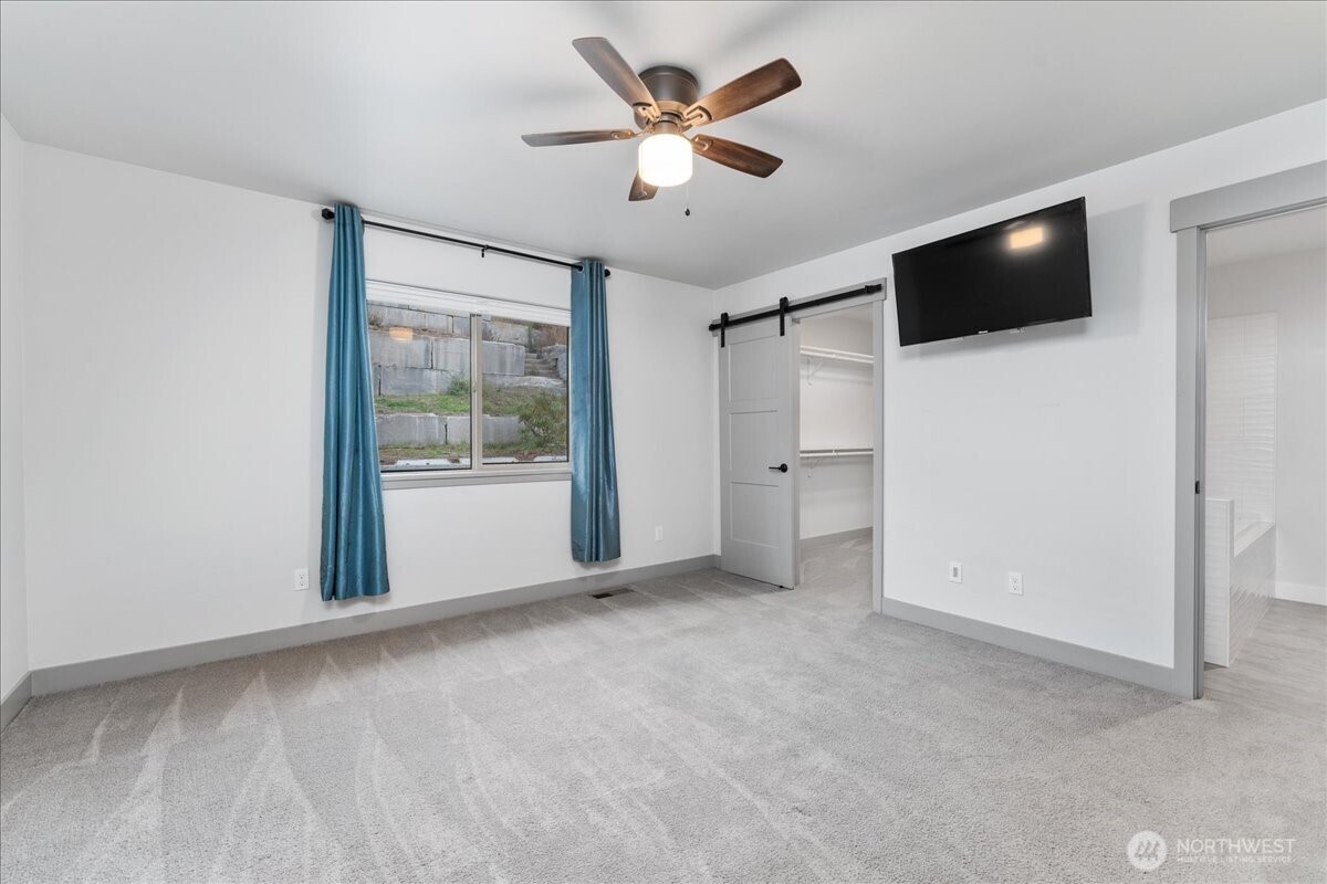 9978 Saska Way Entiat, WA 98822 - Photo 15 of 35 a view of an empty room with a flat screen tv and a ceiling fan