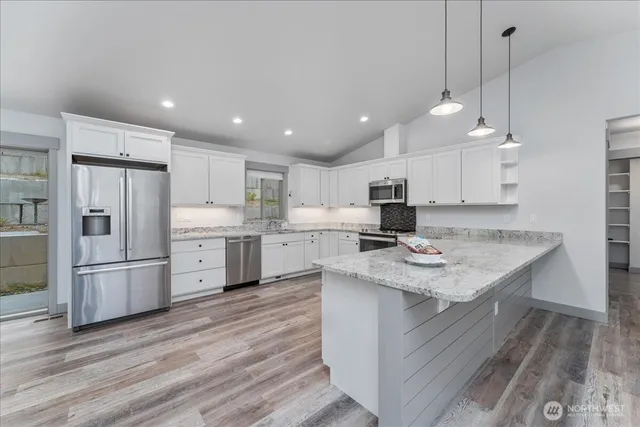 a kitchen with stainless steel appliances granite countertop a sink dishwasher a refrigerator and a stove with wooden floor