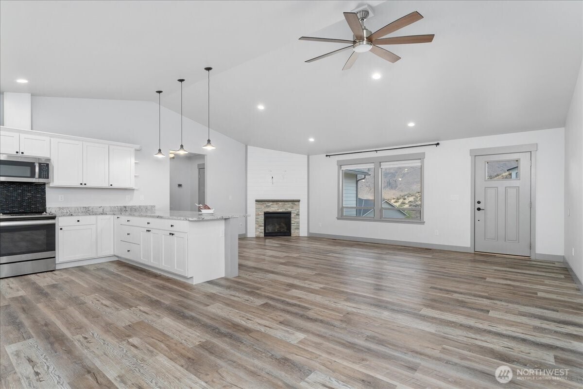 9978 Saska Way Entiat, WA 98822 - Photo 10 of 35 a large kitchen with cabinets wooden floor stainless steel appliances and a fireplace