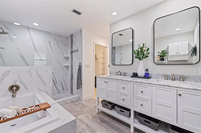 a spacious bathroom with a double vanity sink a mirror and shower