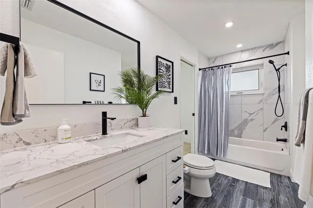 a bathroom with a granite countertop sink toilet and shower