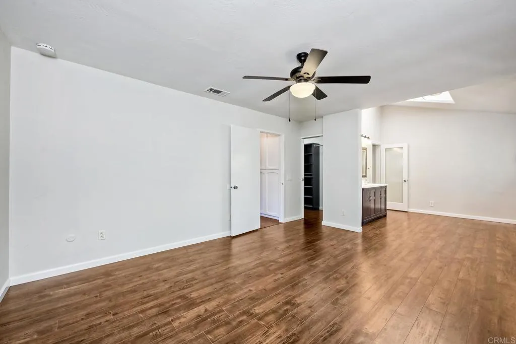 2425 Torrejon Place Carlsbad, CA 92009 - Photo 13 of 61 a view of an empty room with wooden floor and a ceiling fan