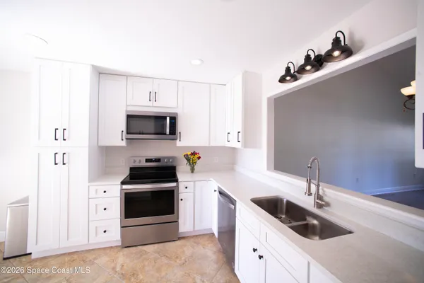 a kitchen with stainless steel appliances a sink stove and white cabinet