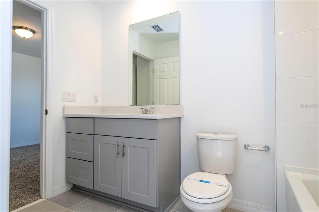 4549 Burrowing Owl Loop St. Cloud, FL 34772 - Photo 34 of 48 a bathroom with a toilet a sink a vanity and mirror