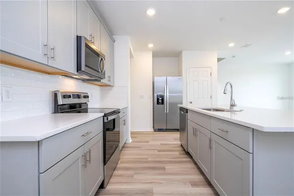 a kitchen with stainless steel appliances a sink dishwasher a refrigerator and a microwave