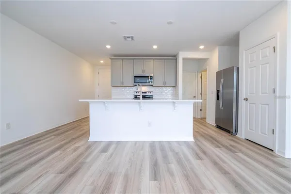 a large kitchen with stainless steel appliances kitchen island a large counter top and a stove top oven
