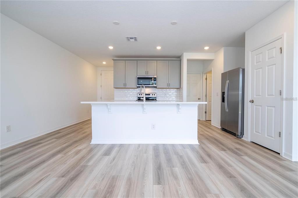 4549 Burrowing Owl Loop St. Cloud, FL 34772 - Photo 7 of 48 a large kitchen with stainless steel appliances kitchen island a large counter top and a stove top oven