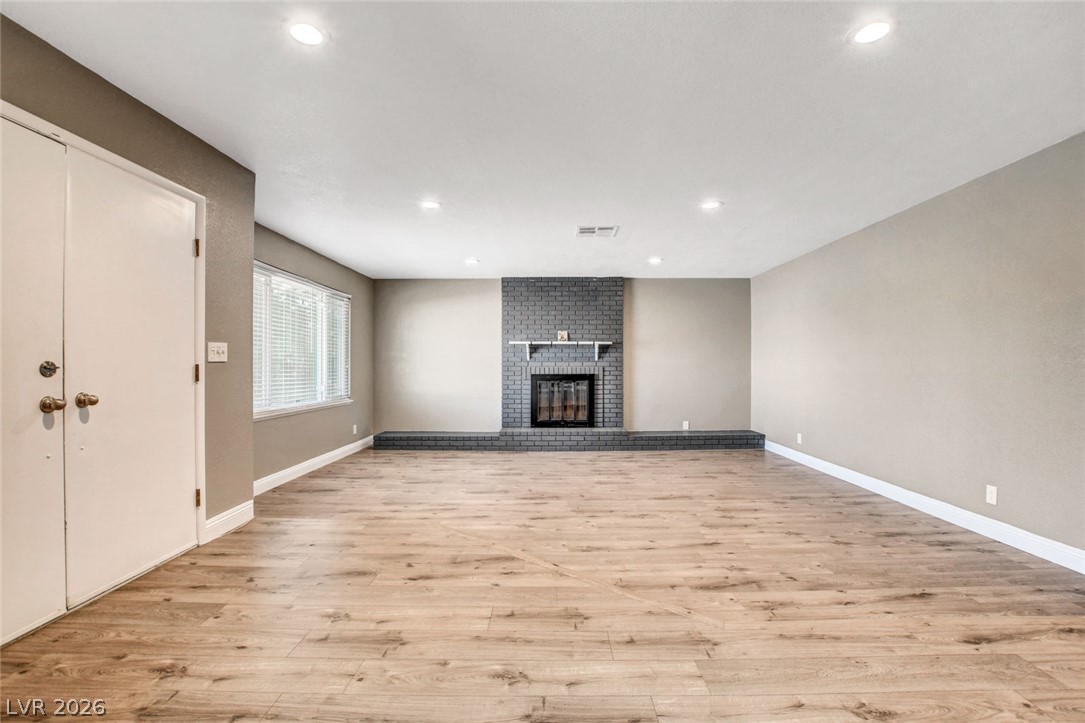 4367 South Mojave Road Las Vegas, NV 89121 - Photo 6 of 53 A well-lit living area showcases rich hardwood flooring and a prominent brick fireplace feature.